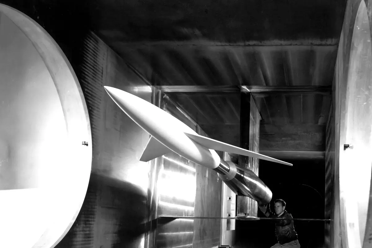 A technician beside a rocket model in a supersonic wind tunnel in 1948