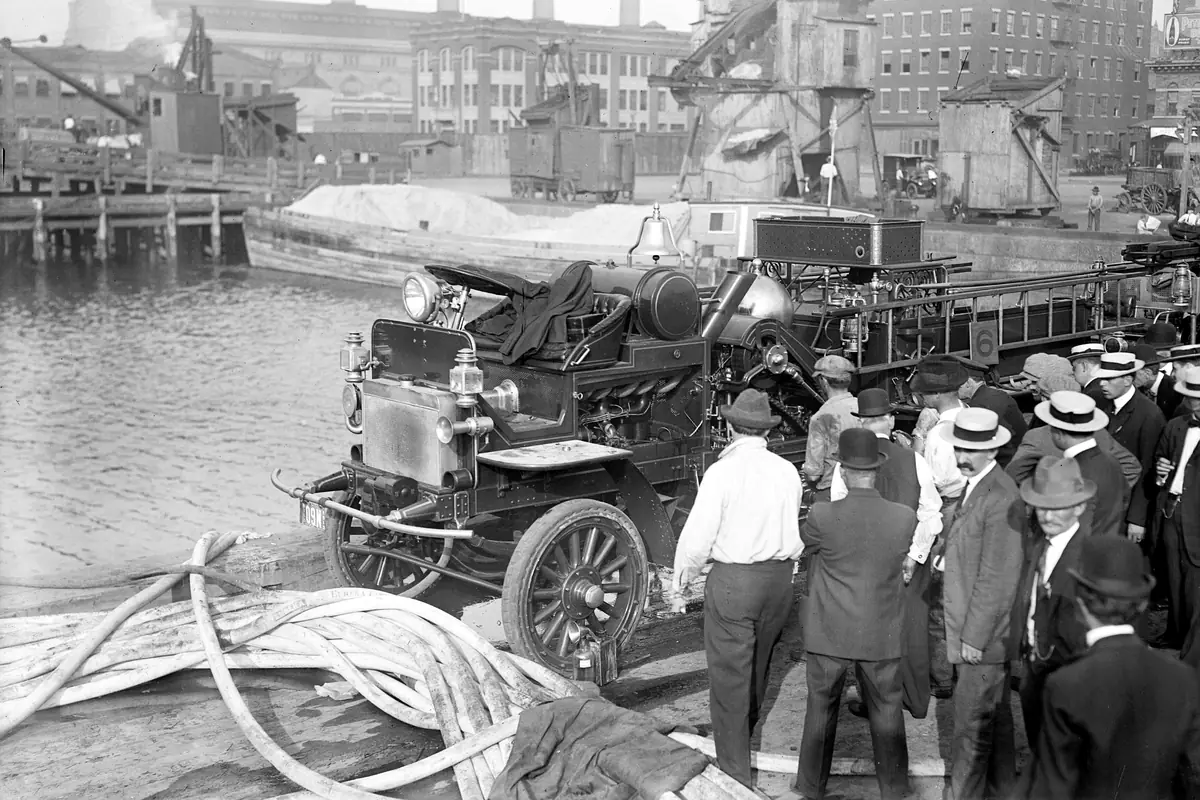 A motor fire engine on a New York pier with hoses and onlookers in 1913